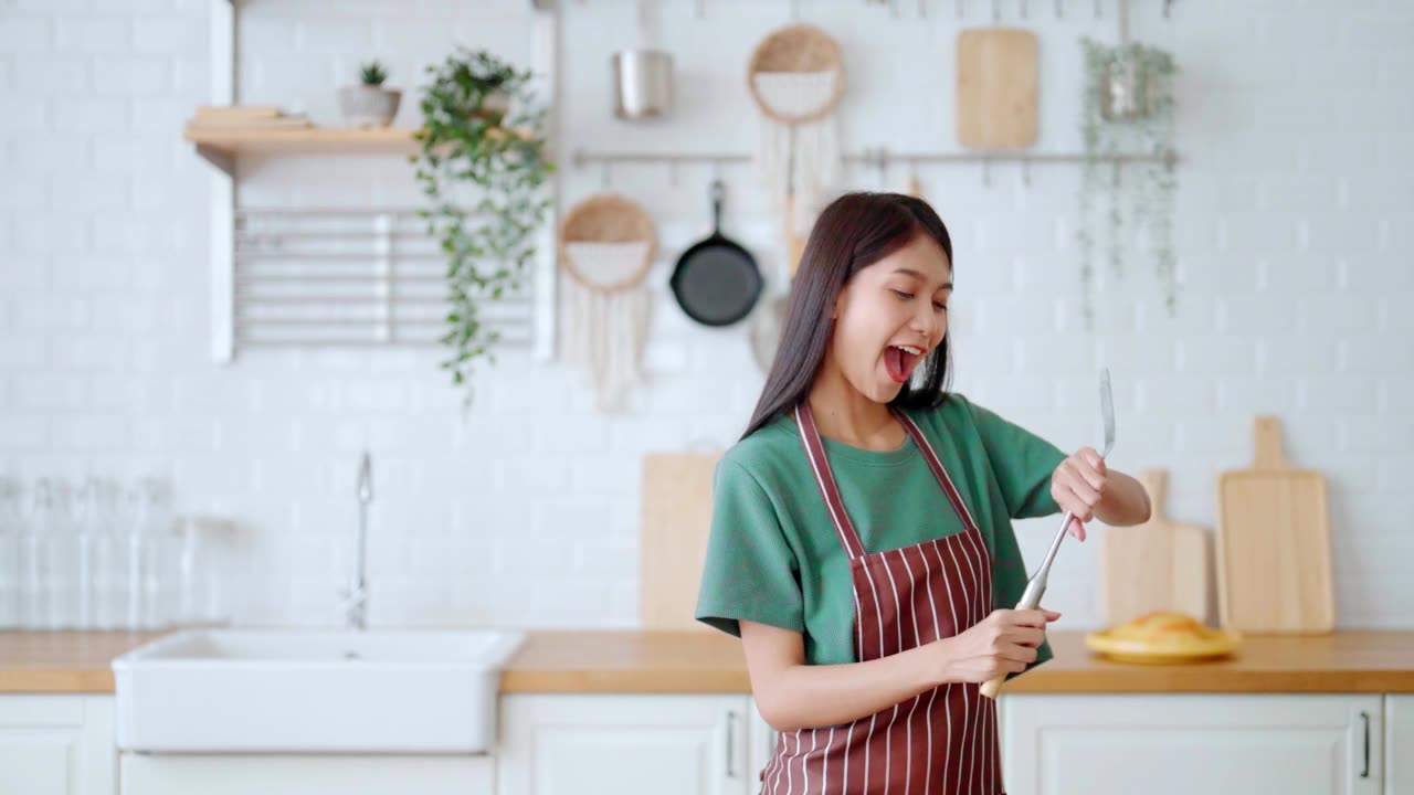 詳情圖-亞洲年輕女子在廚房里跳舞。女性在周末的空閑時(shí)間快樂和放松