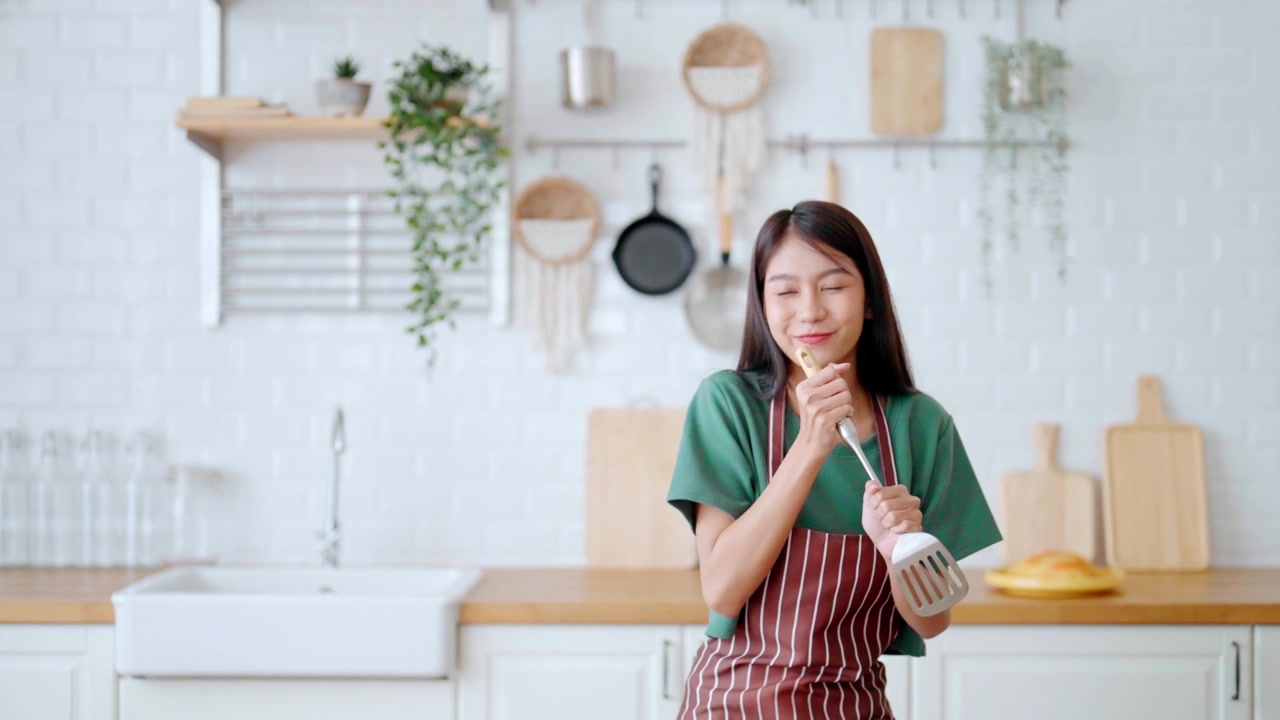 詳情圖-亞洲年輕女子在廚房里跳舞。女性在周末的空閑時(shí)間快樂和放松