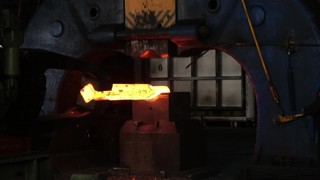 铁匠工厂。用工业锻压机锻造大型铁坯。机器人工作的特写。金属锻造厂的技术设备。大型机器，铁匠移动和加热金属和准备管道的轨道。的blacksm