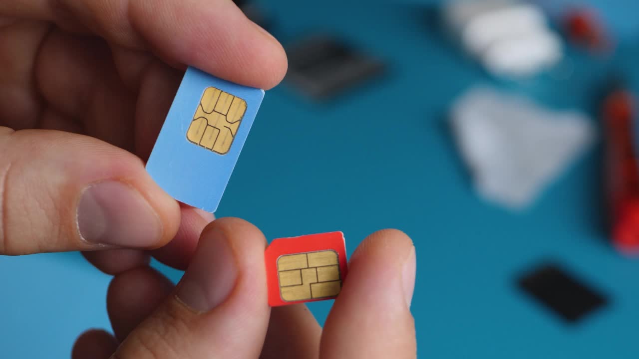 修理工男手持红色微SIM卡和蓝色迷你SIM卡