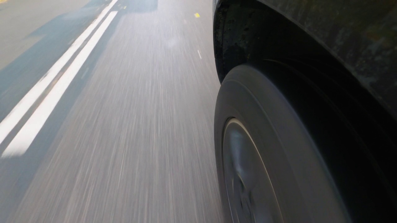 一辆汽车的前轮和中央预留的沥青道路在低视角的左前轮