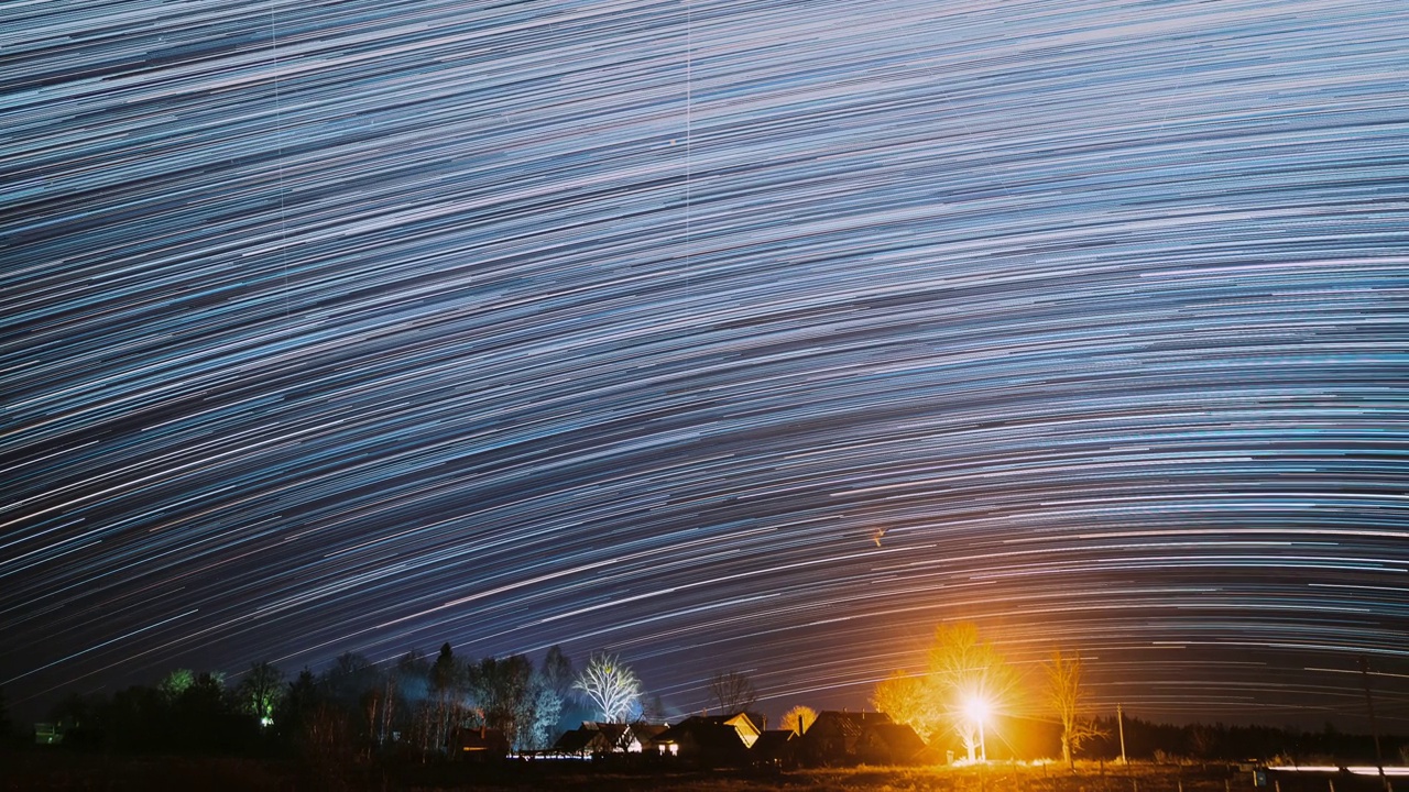 4k超崩夜，村庄上空星空。宇宙的概念。惊人的不寻常的星星效果。明亮的蓝色。天空背景。流星划过深蓝色的天空。时间流逝，时间流逝，时间流逝