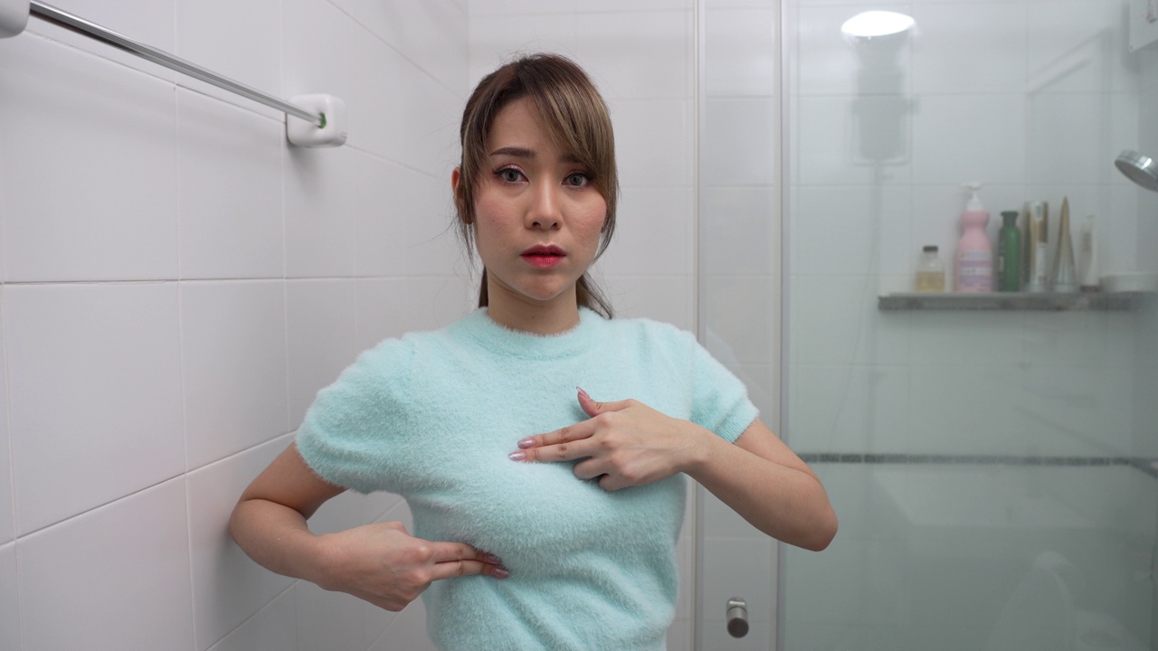 乳腺癌，世界癌症日。年轻漂亮的女人在检查乳房肿块或癌症。