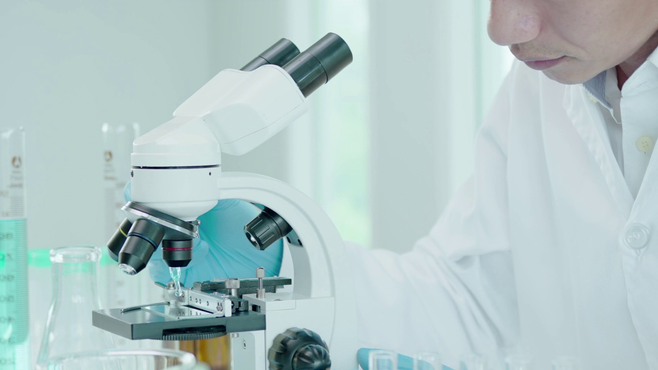 男科学家在先进的科学实验室分析生化样品。医学专业人员用显微镜观察病毒的微生物发育。实验室生物技术研究。