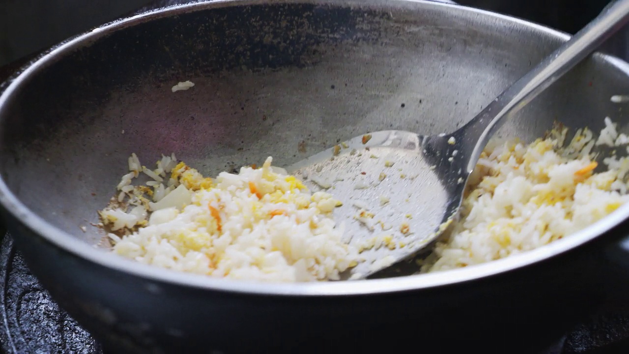 厨师正在炉子上的热锅里做炒饭。