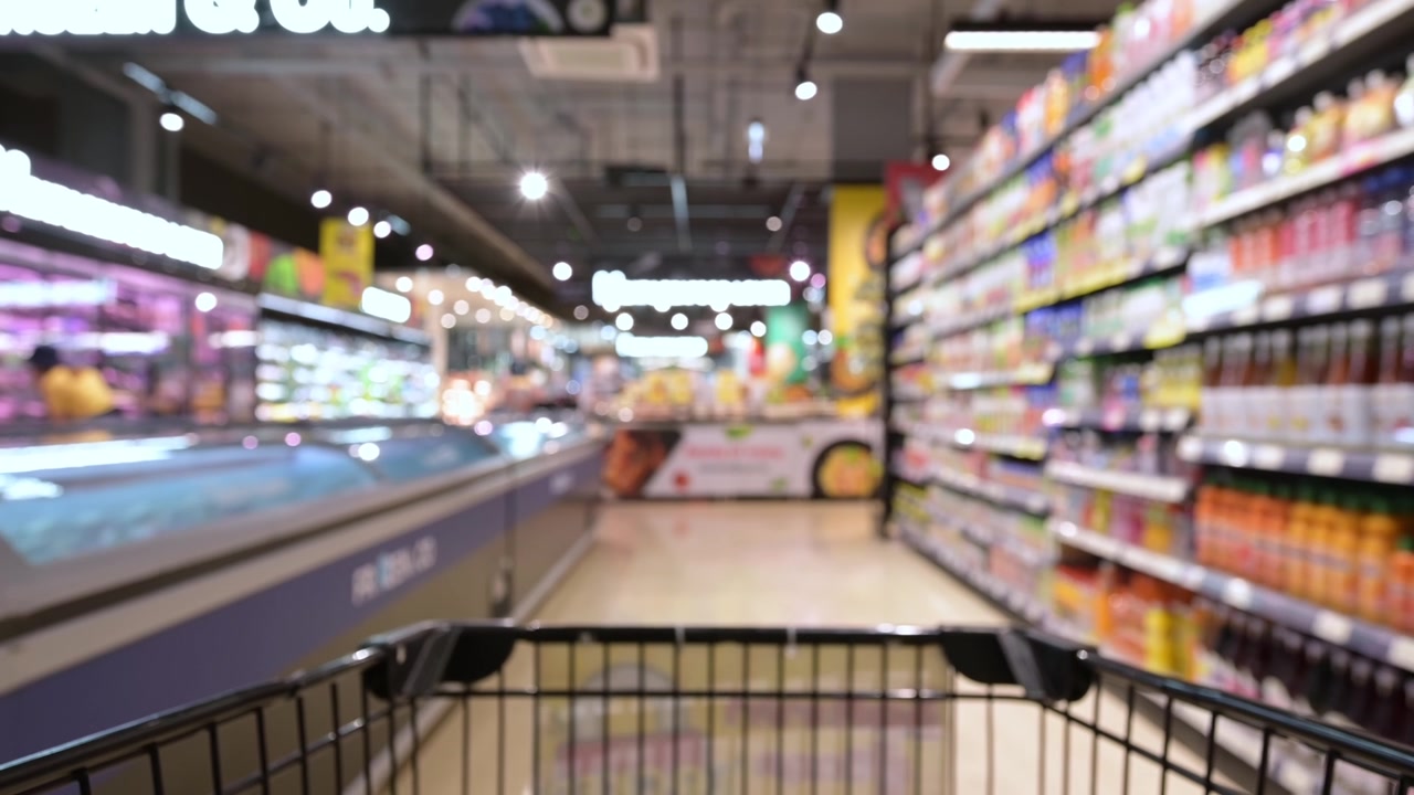 详情图-模糊的购物车通过食品货架内部散焦背景在超市。一个人在超市里推着购物车的慢动作镜头。