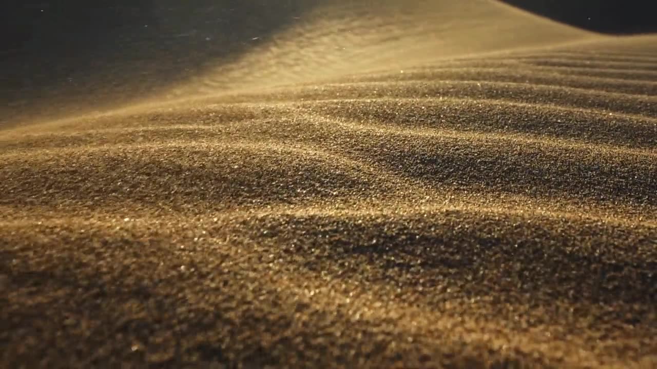 详情图-沙漠中的沙尘暴。微距拍摄的沙粒被风吹走。在落日的余晖中，摄像机沿着沙漠中的沙丘表面移动。沙子在风中飘动。慢镜头