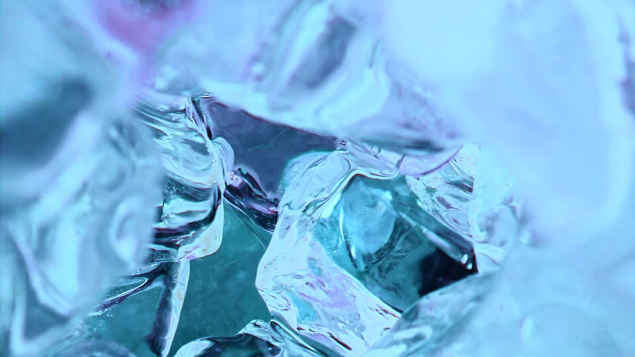 1000帧/秒的慢动作，水液体倒在蓝色冰块中。超宏慢动作1000fps。极端近距离视角的蓝色液体倒在冰块上的相机移动内部远离我们。
