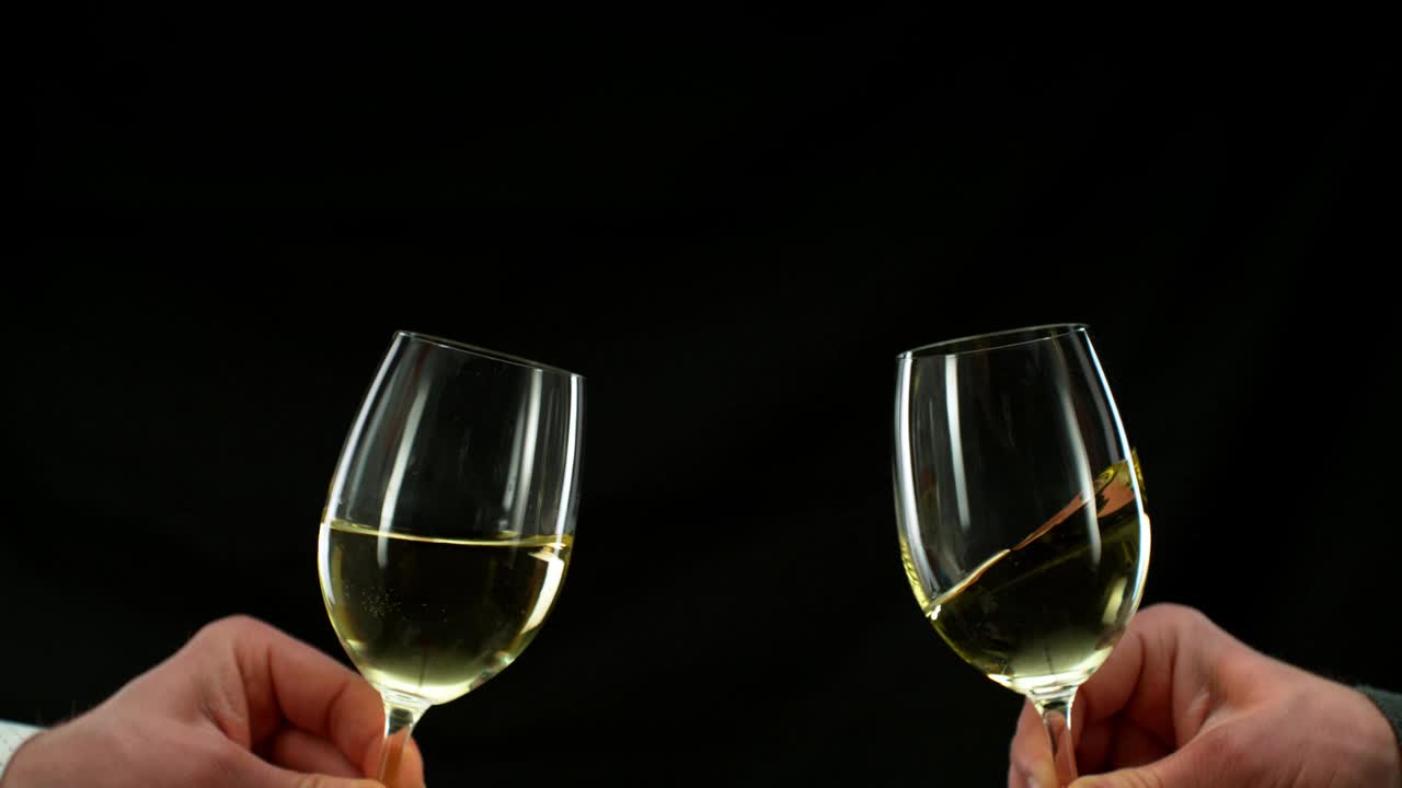 超级慢动作的白葡萄酒酒杯在干杯的手势。