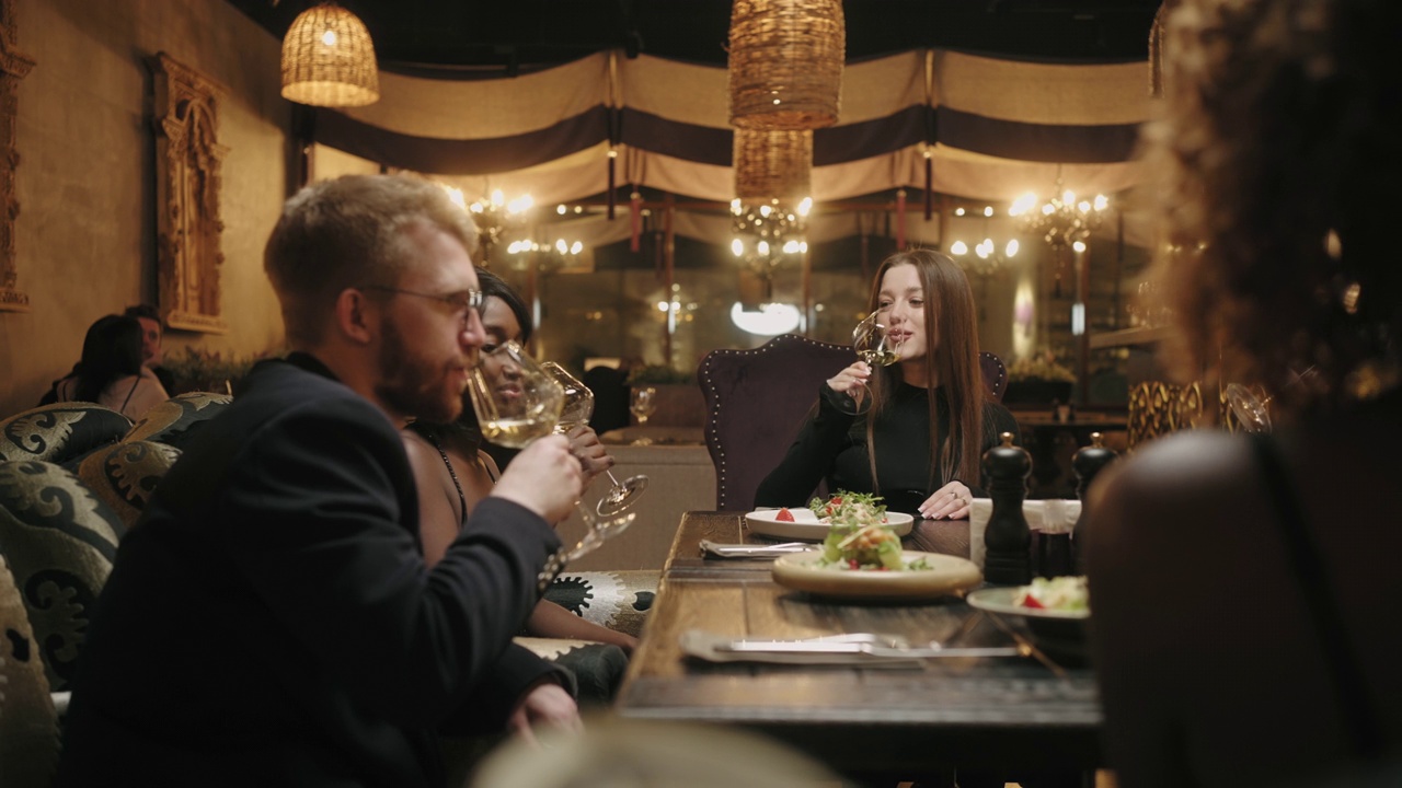 多民族朋友在餐厅庆祝生日，女人敬酒，人们碰杯
