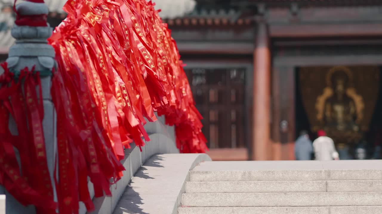 白色石桥上的红色绸带随风摇曳，寺庙中的佛像背景，4k慢动作镜头。