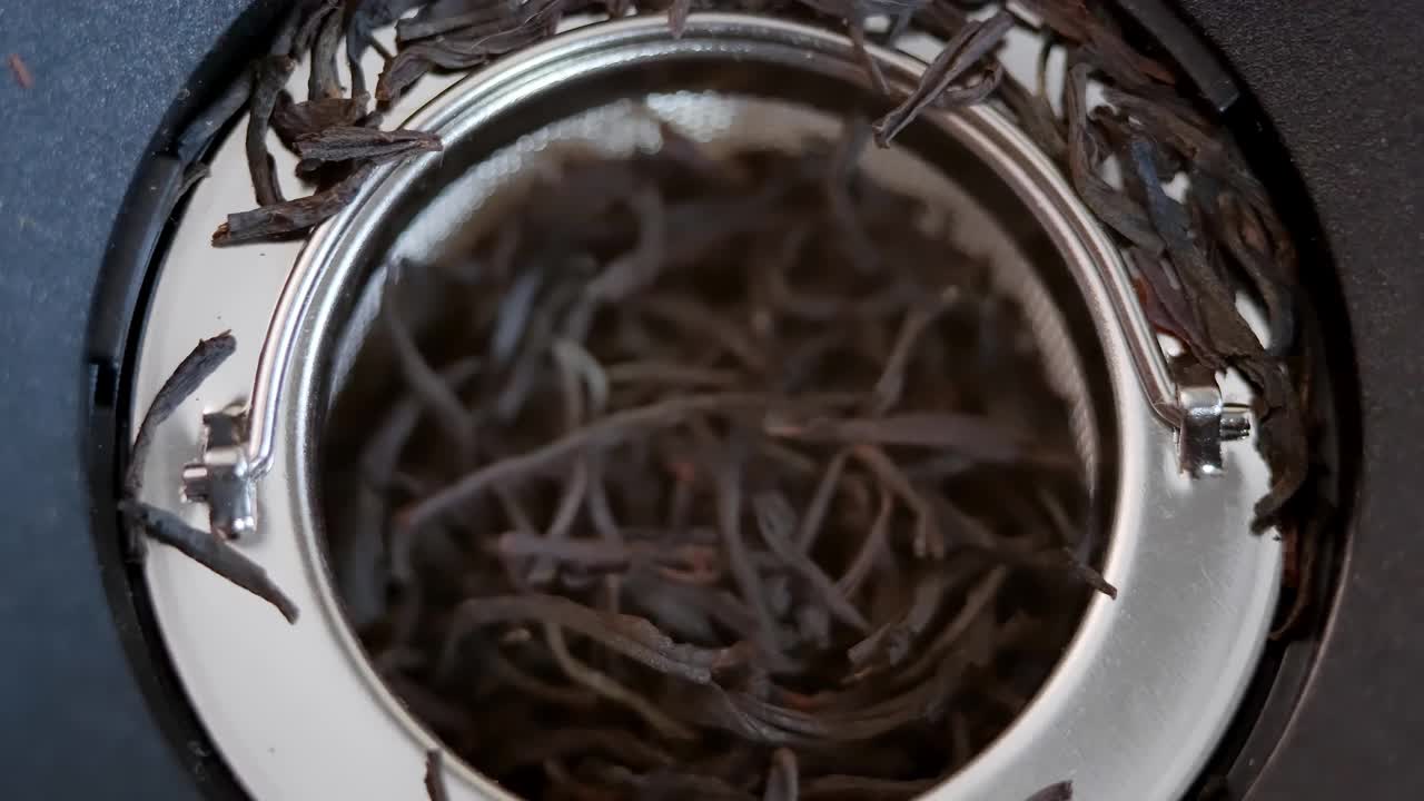 把干茶叶倒进茶壶里。玻璃罐大叶红茶。