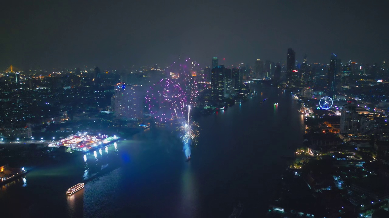 空中无人机视角多色烟花表演在天空之城。除夕。摩天大楼和城市景观庆祝夜晚的灯光