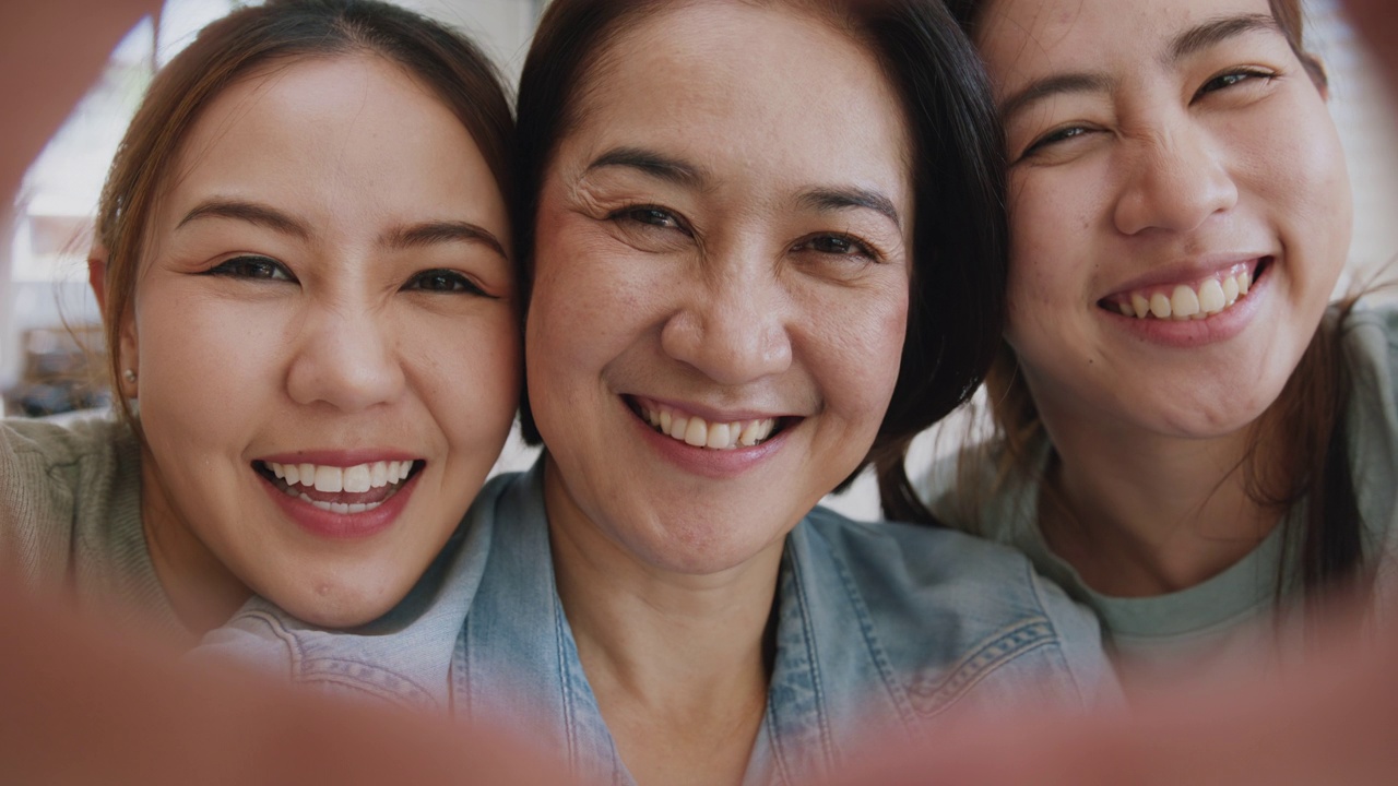 妈妈和女儿正在做心形的手势，标志着快乐的亚洲家庭自拍照