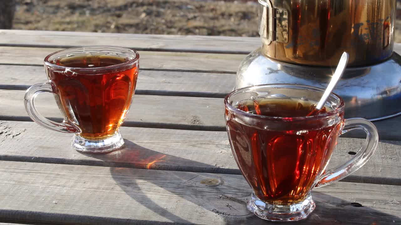 在杯子里的茶里搅拌糖的男人的手。一杯土耳其红茶