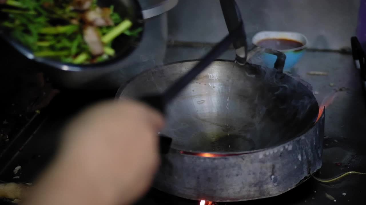 厨师准备烹饪食物在厨房餐厅用辣椒和热煎锅煸炒水含羞草，泰国传统食物。