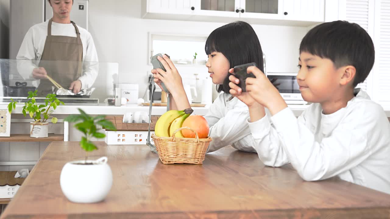 男人在厨房做饭，孩子们在餐厅玩游戏