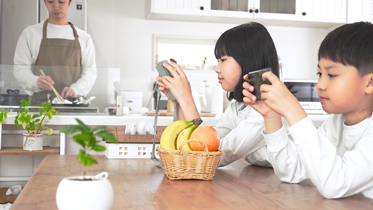 男人在厨房做饭，孩子们在餐厅玩游戏