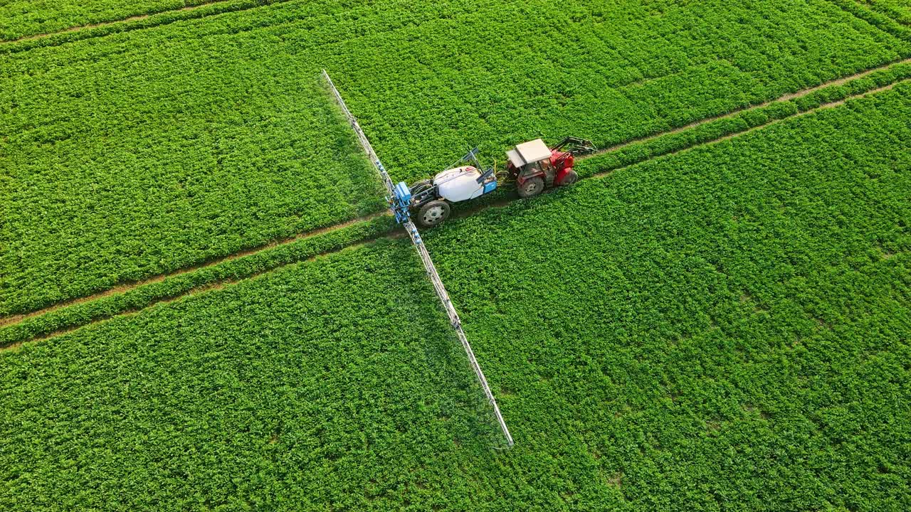 向绿地喷洒杀虫剂的农业机械。农用拖拉机在田间喷洒喷雾器、除草剂和杀虫剂
