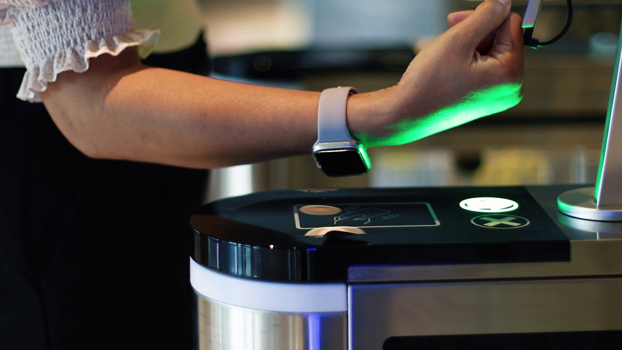 一名女员工用手腕上的智能手表扫描门禁打开门。