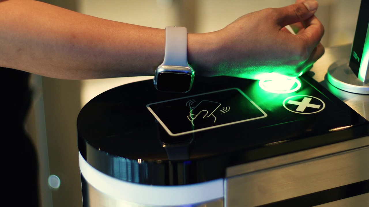 一名女员工用手腕上的智能手表扫描门禁打开门。