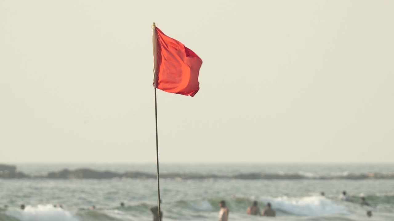 禁止游泳标志。红旗海滩。人们打破规则。不安全的侵犯。
