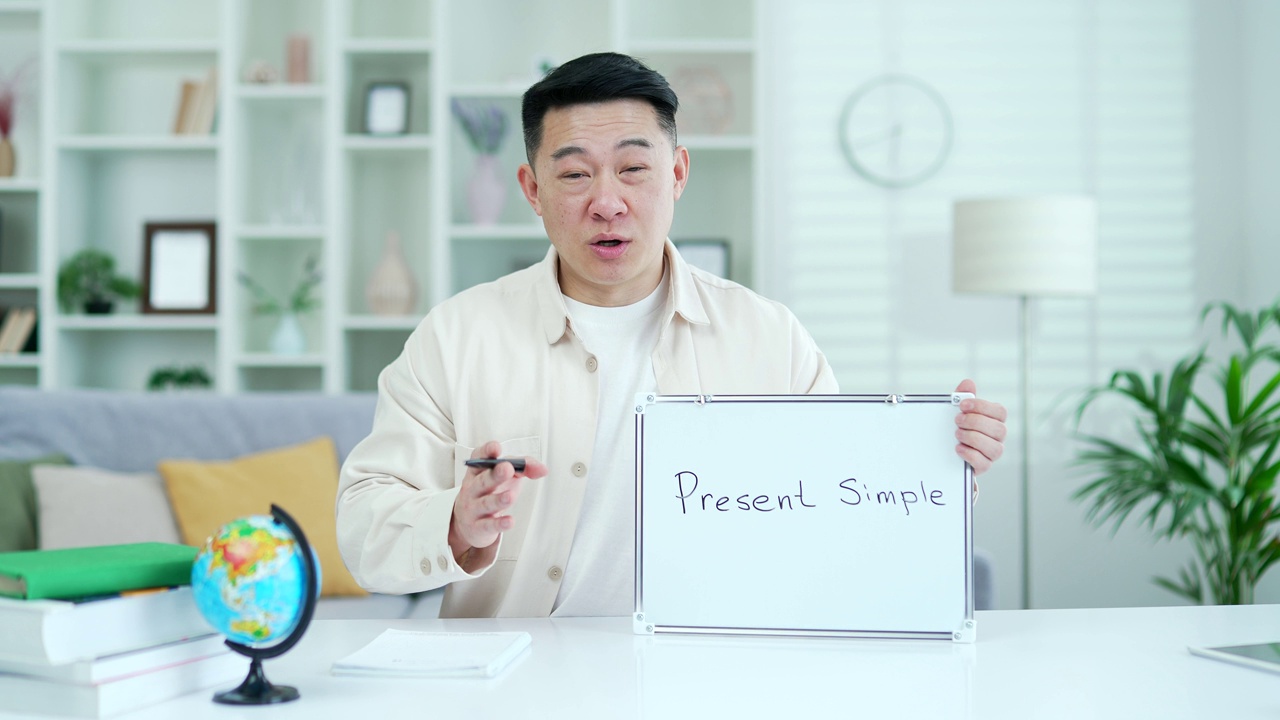 摄像头的观点。自信的亚洲私人教师在家庭办公室里看着镜头，给学生上视频电话英语课。