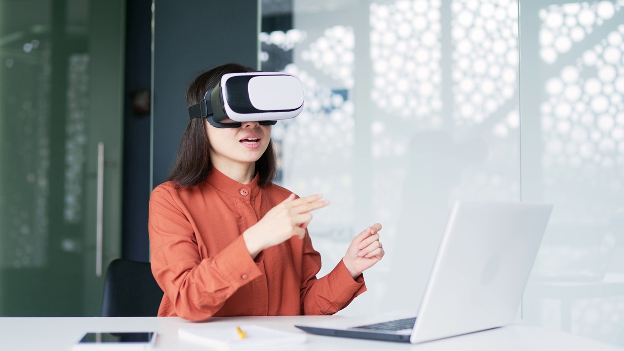 亚洲成功女商人使用VR眼镜在虚拟现实模拟器中进行视频通话和在线聊天