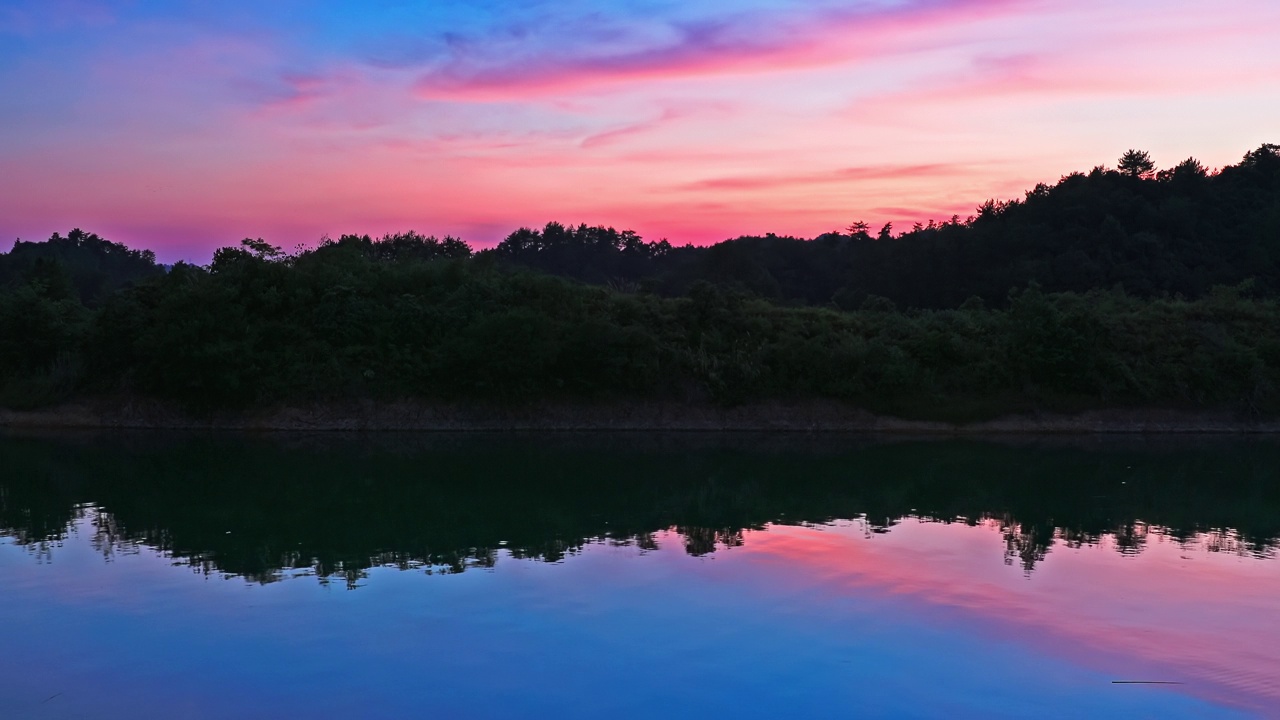 夕阳下，清澈的湖面映着彩云