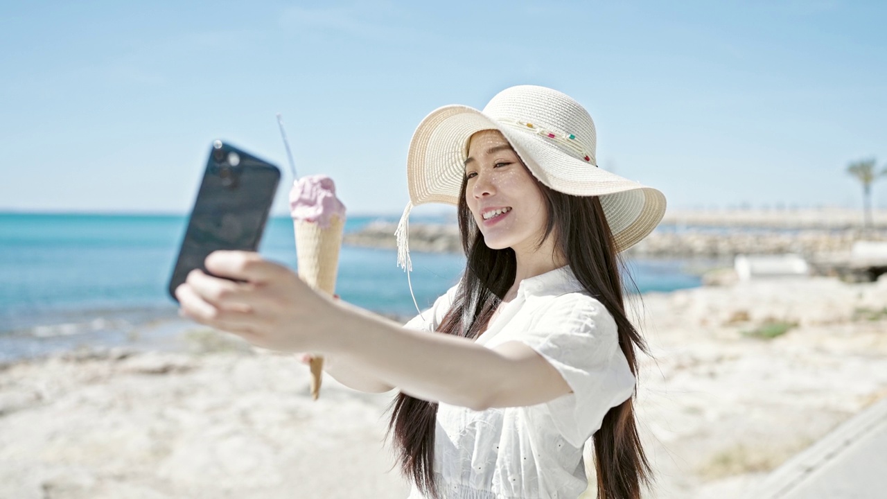 详情图-年轻的中国女游客在海边边吃冰淇淋边用智能手机自拍