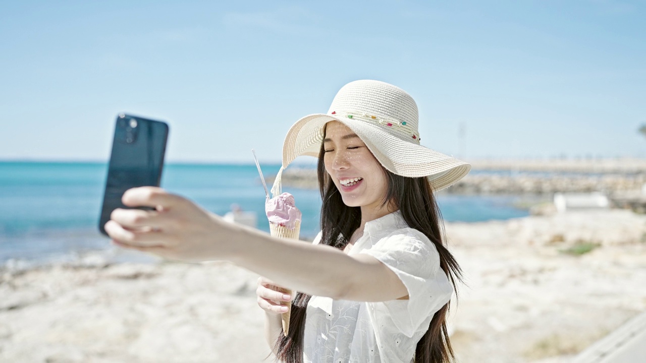 详情图-年轻的中国女游客在海边边吃冰淇淋边用智能手机自拍