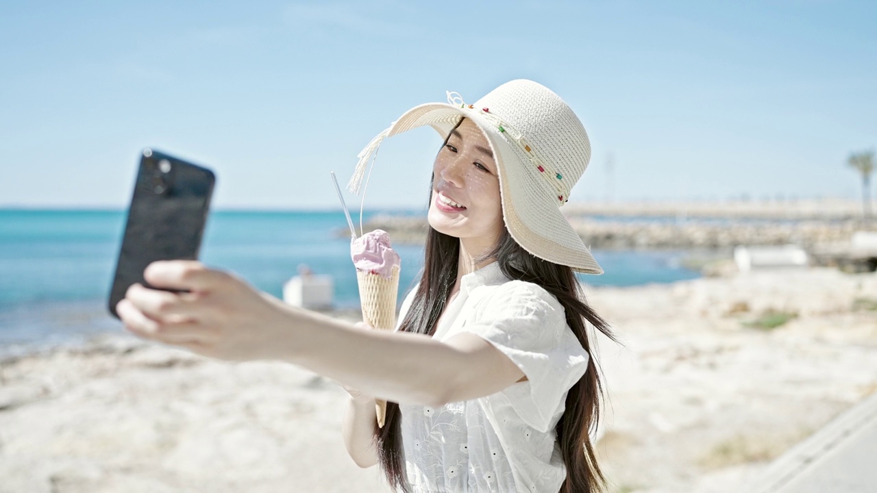 详情图-年轻的中国女游客在海边边吃冰淇淋边用智能手机自拍