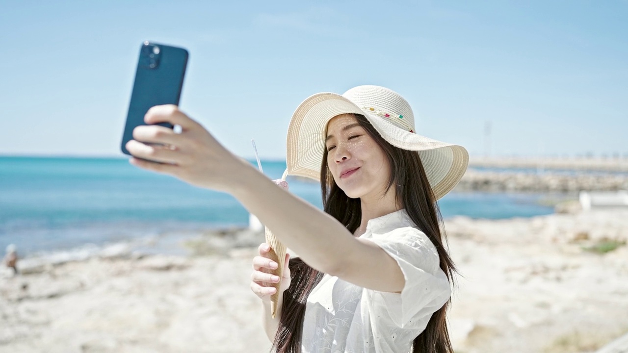 详情图-年轻的中国女游客在海边边吃冰淇淋边用智能手机自拍