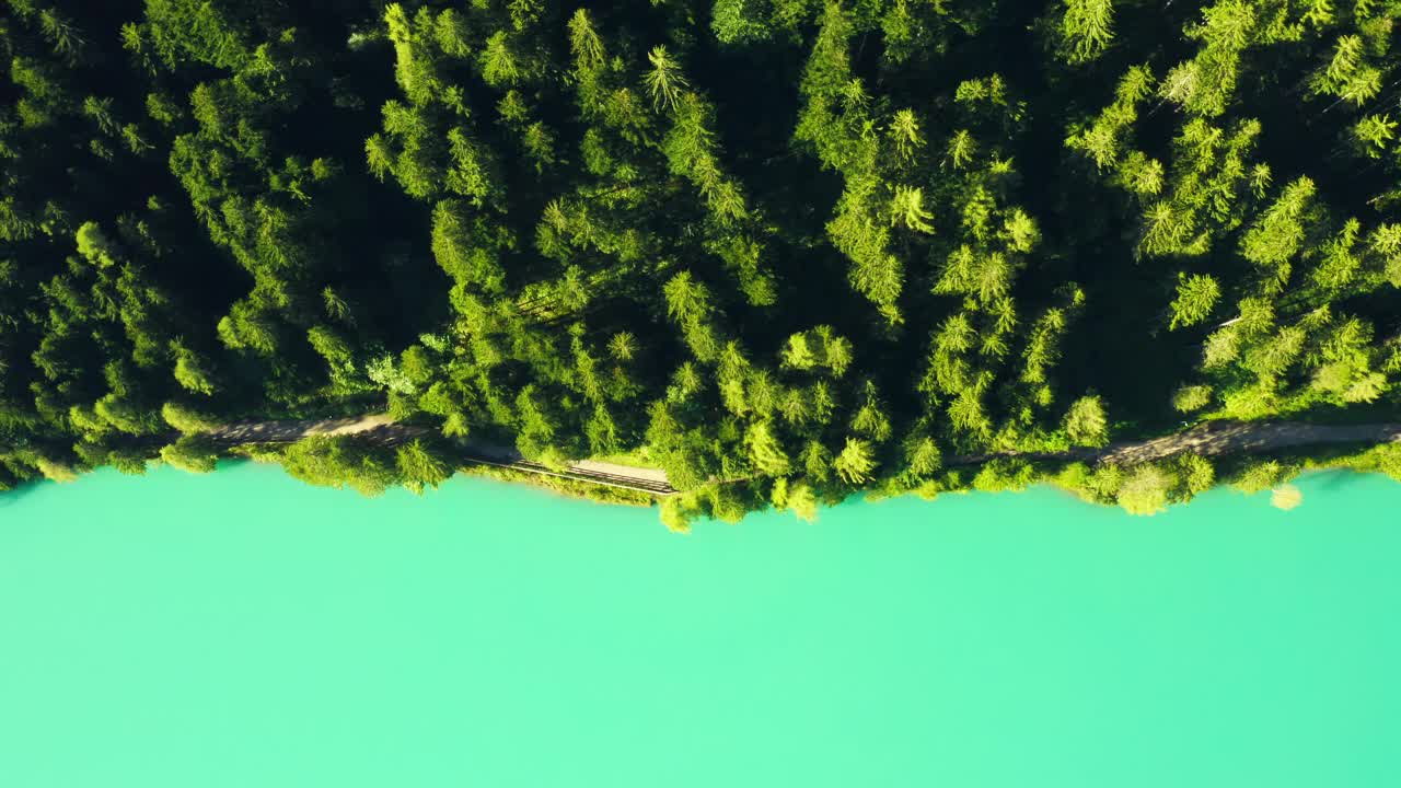 清澈的绿松石湖坐落在郁郁葱葱的绿树在风景秀丽的山上，创造一个充满活力的景观在一个阳光明媚的夏日。