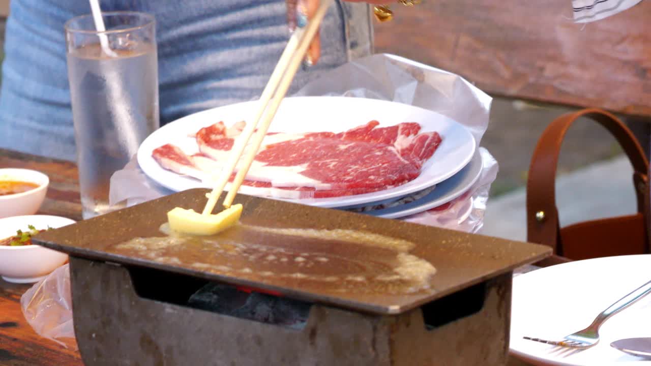 在餐馆烤牛排时，在热锅上涂黄油。