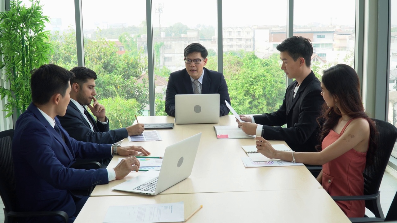 一群亚洲商务人士在高层办公室开会讨论Windows。首席执行官经理在会议室与公司业务团队谈话。