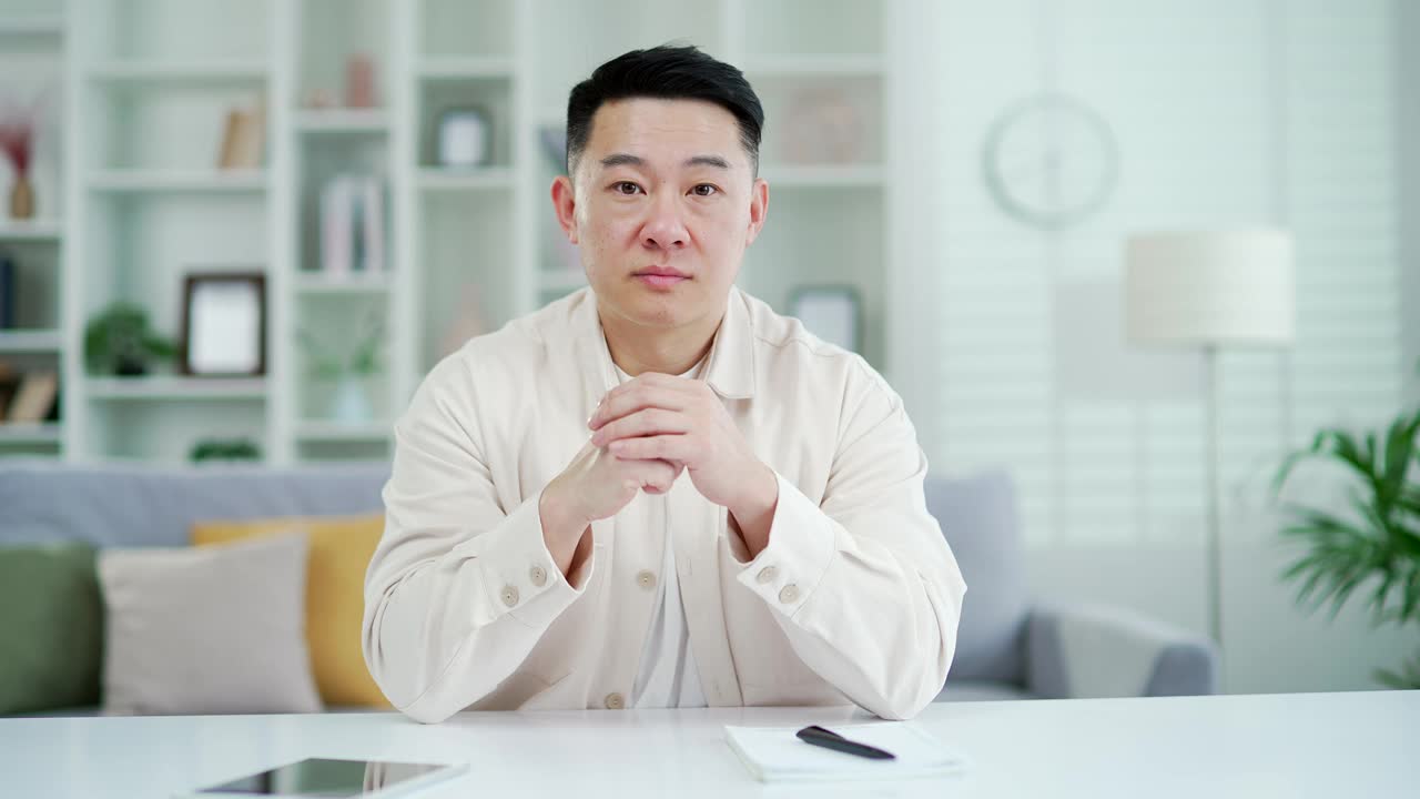 摄像头的观点。一名亚洲男子一边看着摄像机一边观看视频电话课程或培训