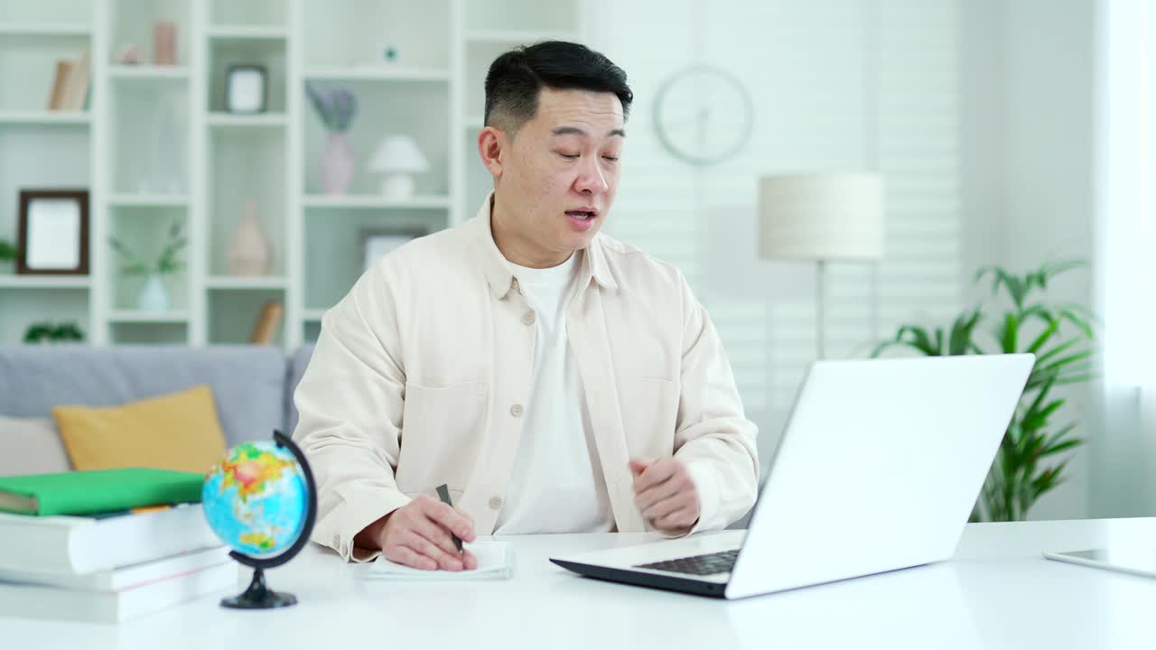 亚洲家庭教师坐在家里的办公室里，用笔记本电脑进行视频通话课程或培训
