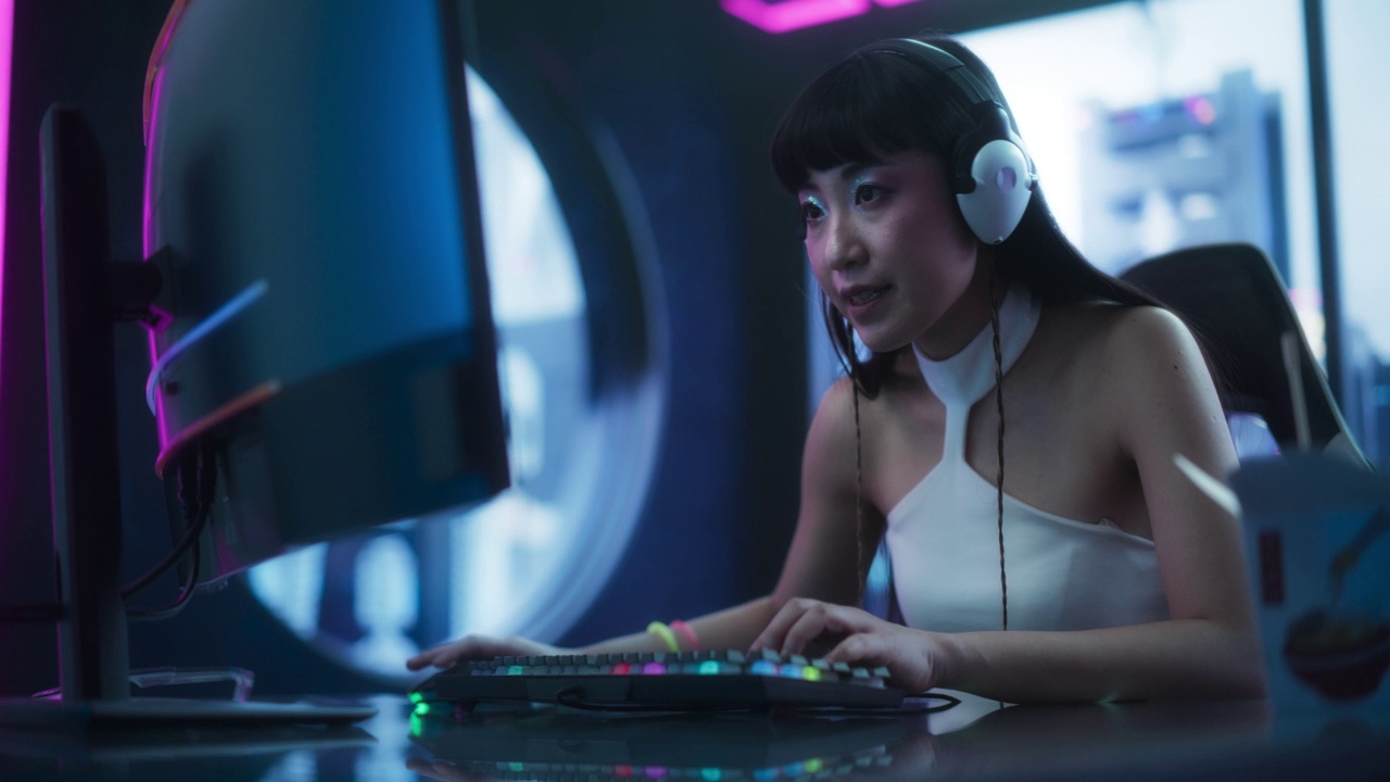 詳情圖-興奮的日本Cosplay女孩在桌面電腦上玩在線電子競技錦標(biāo)賽，周圍是賽博朋克風(fēng)格的背景?；ヂ?lián)網(wǎng)流媒體，游戲，視頻游戲和社交網(wǎng)絡(luò)的概念