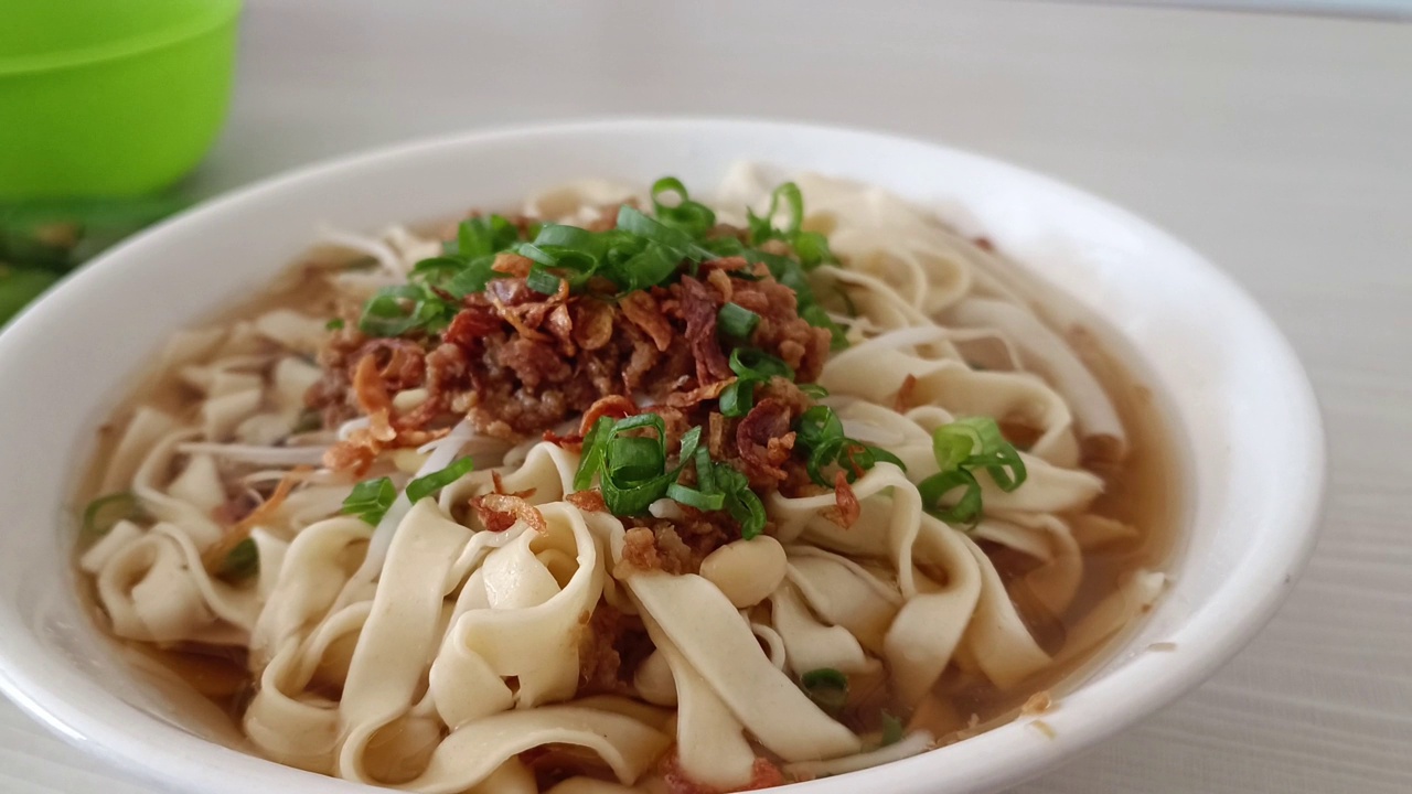 传统的烹饪菜肴:一碗宽面条和猪肉汤里的饺子