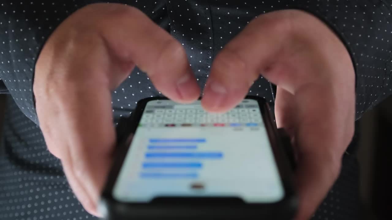 一名身穿黑色办公衬衫的男子正在工作时快速地在网上聊天中输入信息。