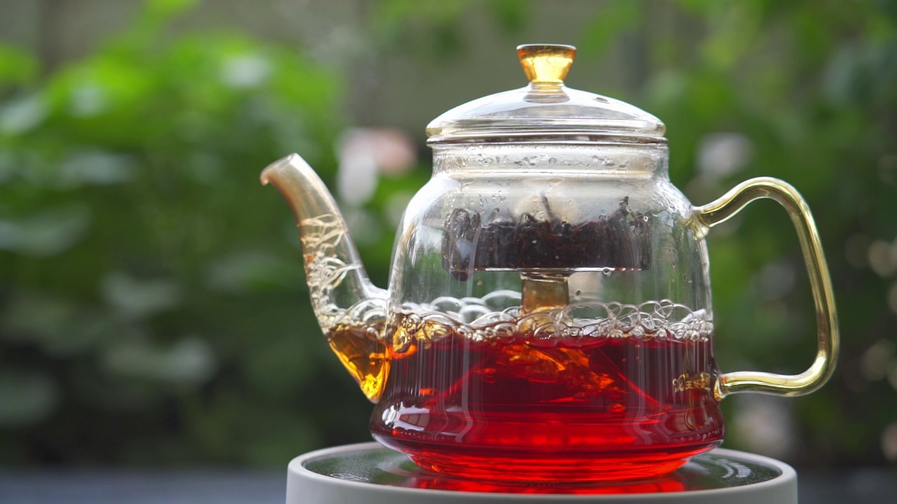 花园电炉上玻璃茶壶冲泡红茶的高架慢动作