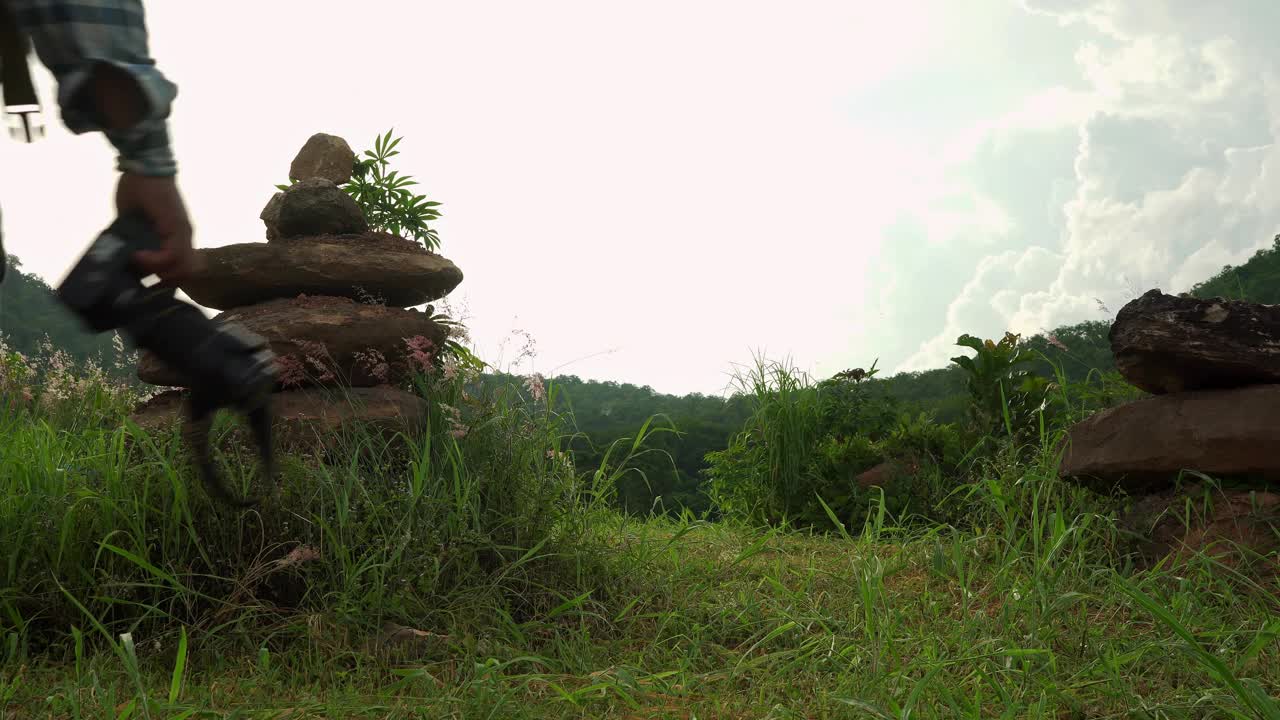 独自旅行的男性背包客拿着相机。大自然，森林，草原，丘陵，美丽的岩石山脉。