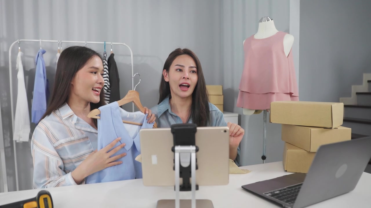 詳情圖-亞洲女性企業(yè)主在時(shí)裝商店展示服裝，在智能手機(jī)前錄制視頻視頻直播，向顧客出售時(shí)裝，網(wǎng)上購物概念。
