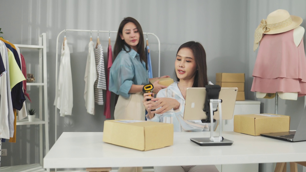 詳情圖-亞洲女性企業(yè)主在時(shí)裝商店展示服裝，在智能手機(jī)前錄制視頻視頻直播，向顧客出售時(shí)裝，網(wǎng)上購(gòu)物概念。