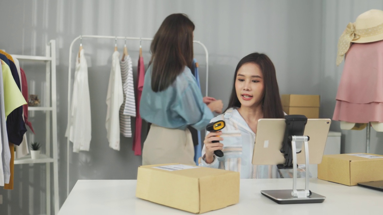 詳情圖-亞洲女性企業(yè)主在時(shí)裝商店展示服裝，在智能手機(jī)前錄制視頻視頻直播，向顧客出售時(shí)裝，網(wǎng)上購(gòu)物概念。