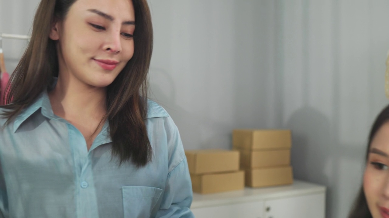詳情圖-亞洲女性企業(yè)主在時(shí)裝商店展示服裝，在智能手機(jī)前錄制視頻視頻直播，向顧客出售時(shí)裝，網(wǎng)上購(gòu)物概念。