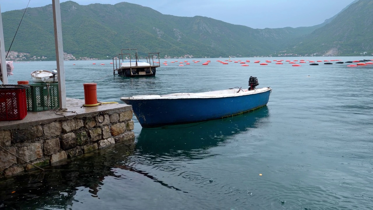 详情图-有马达的捕鱼木船在海上下雨时停泊在石码头。