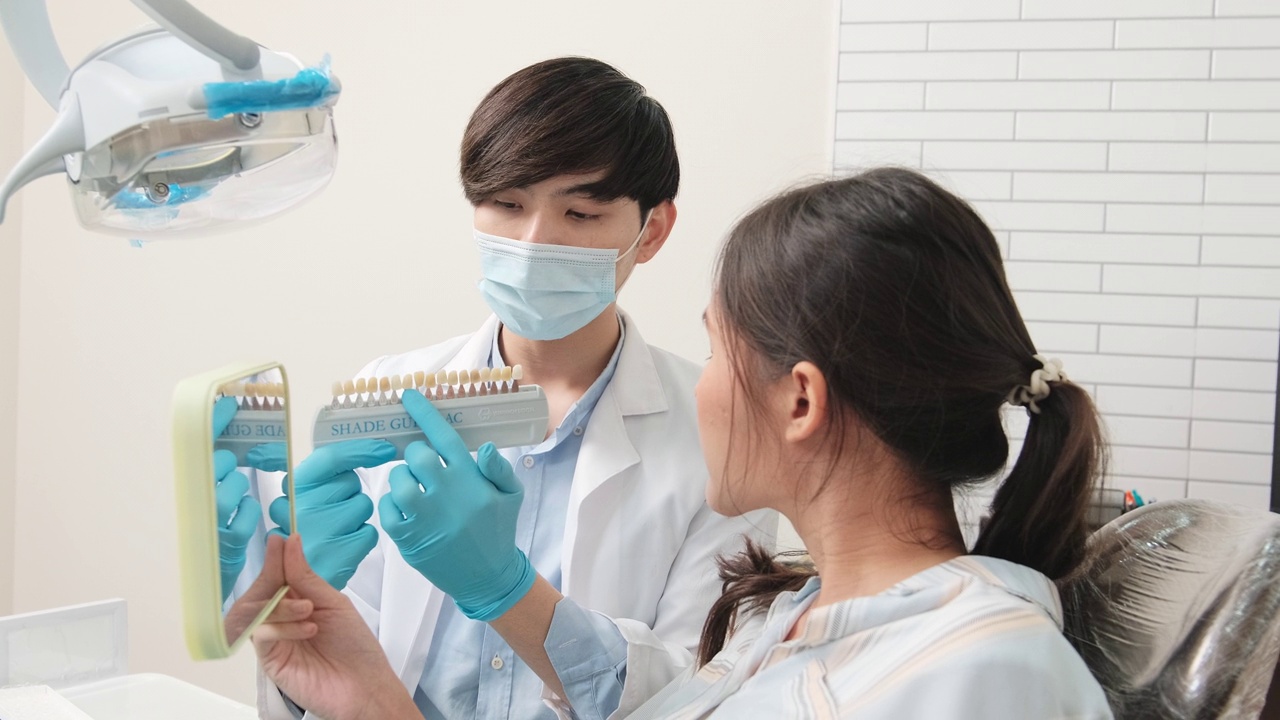 一名亚洲男牙医在牙科诊所向一名女病人讲解牙齿护理。