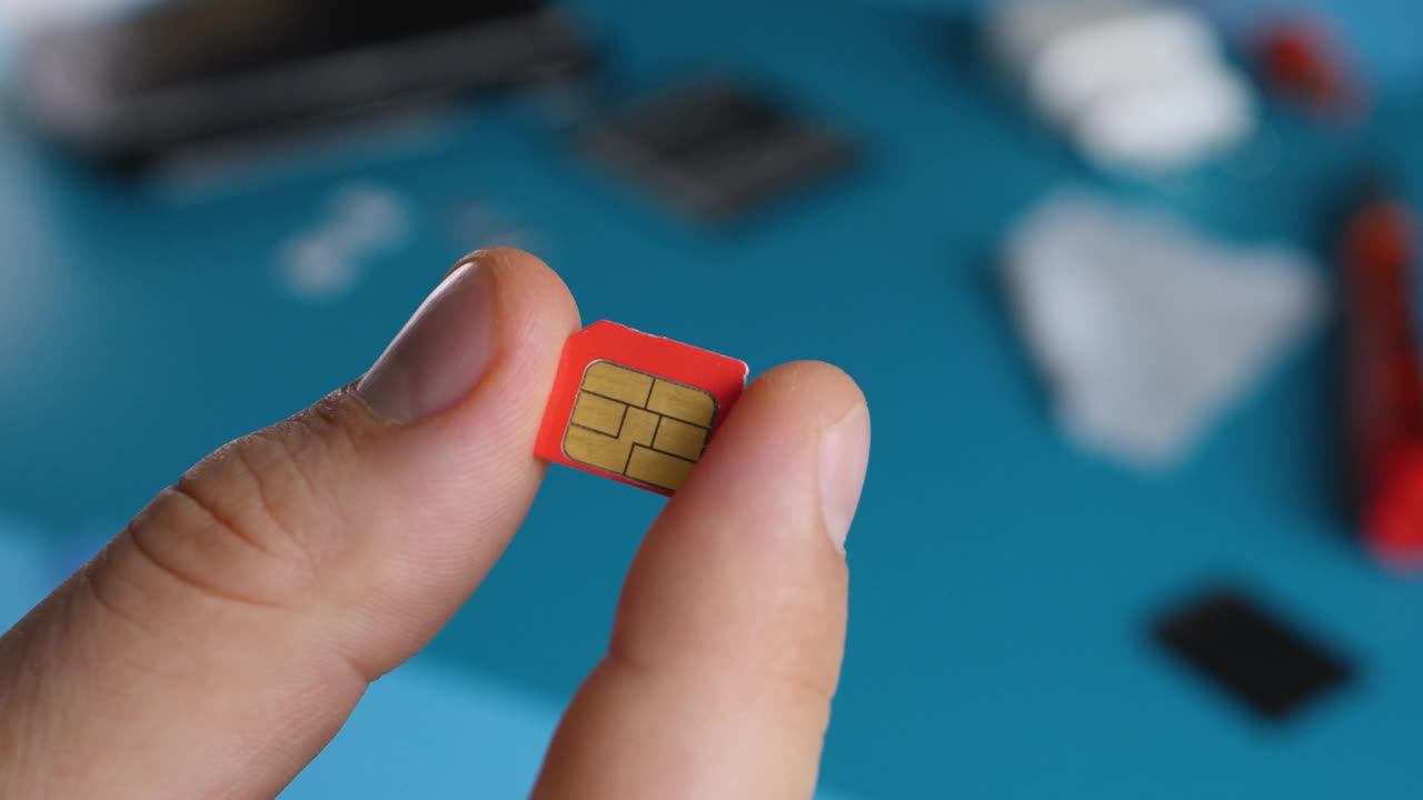维修服务处，男子手持红色微型SIM卡